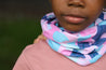 Close up of young girl wearing a pink, blue, navy and mint Infinity Band or snood as a neckwarmer wearing a pink t-shirt.