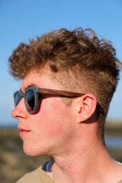 Made with sustainable speckled charcoal wheat straw or coffee residue frame and walnut wood temples, these stylish shades are lightweight, comfortable and eco-friendly with their plastic alternative materials. Fitted with UV400 polarised lenses in a smoke black colour and subtle logo is engraved on the temples. Sunglasses come with a padded pouch and microfibre cleaning cloth.