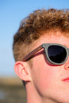 Made with sustainable speckled charcoal wheat straw or coffee residue frame and walnut wood temples, these stylish shades are lightweight, comfortable and eco-friendly with their plastic alternative materials. Fitted with UV400 polarised lenses in a smoke black colour and subtle logo is engraved on the temples. Sunglasses come with a padded pouch and microfibre cleaning cloth. 