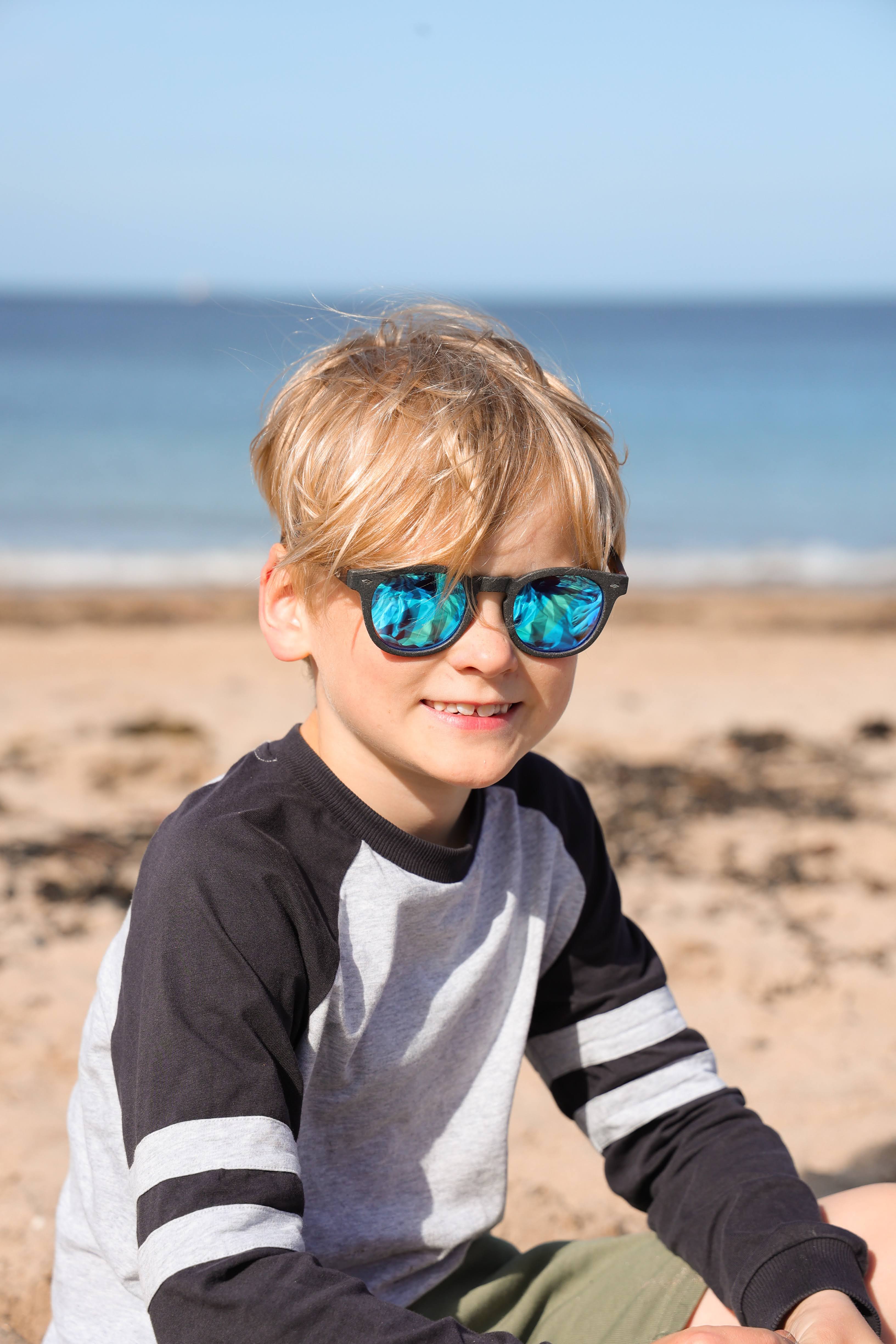 Made with a sustainable speckled wheatstraw frame with walnut wood temples, it's lightweight and comfortable. Fitted with UV400 polarised lenses. Our large child/teen/small adult frame and provides a neater fit without compromising on eye protection.