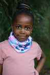 Young girl outdoors in nature wearing the pink, turquoise and navy Infinity Band (snood) around her neck with a pink t-shirt to match.