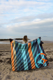 Sustainable waterproof picnic blanket made from recycled polyester, oversized yet packable as it folds flat into a laptop size to slide into a backpack. Zip corner pocket and stake loops and sand pockets to keep it in place. 