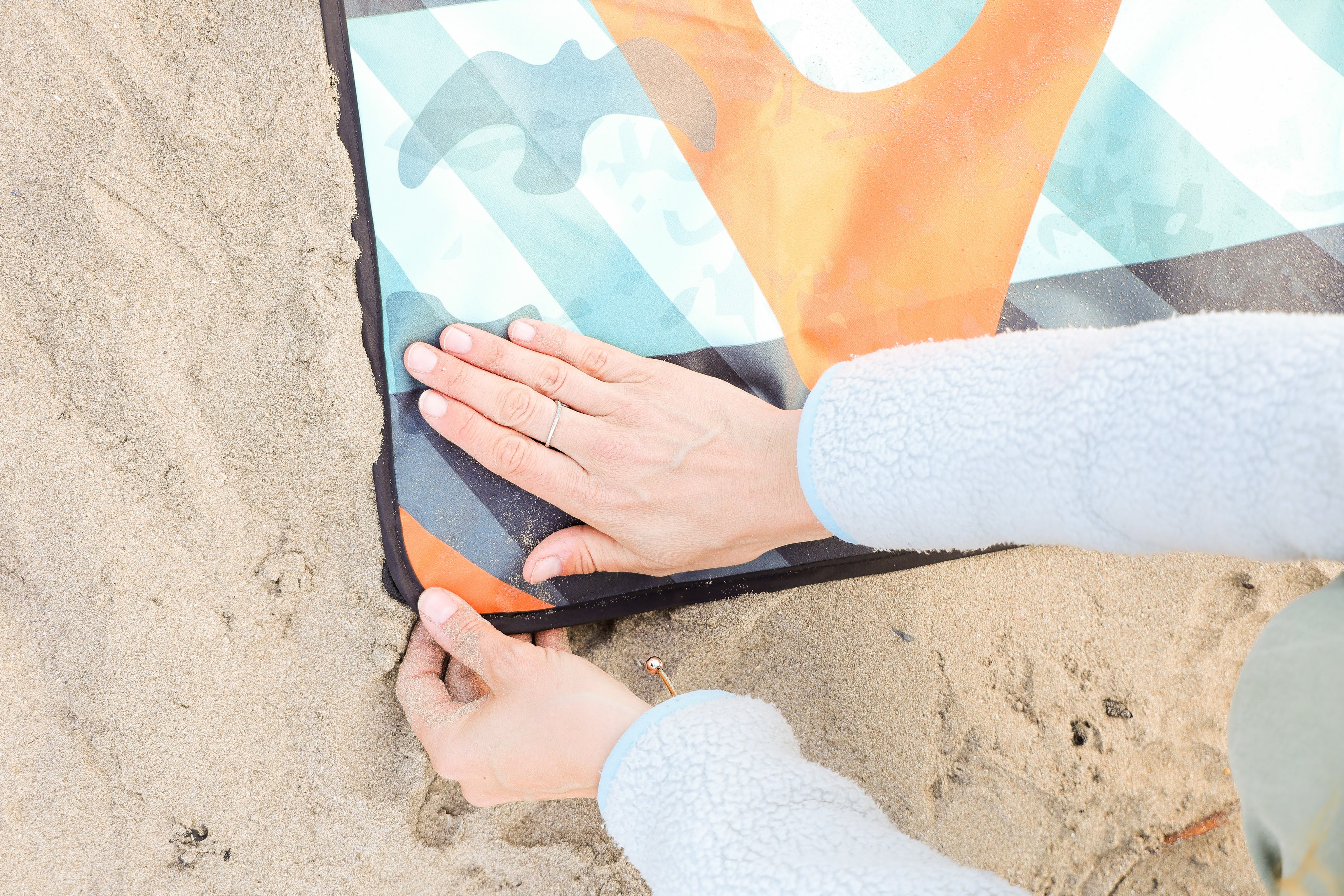 Sustainable waterproof picnic blanket made from recycled polyester, oversized yet packable as it folds flat into a laptop size to slide into a backpack. Zip corner pocket and stake loops and sand pockets to keep it in place. 