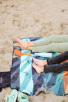 Sustainable waterproof picnic blanket made from recycled polyester, oversized yet packable as it folds flat into a laptop size to slide into a backpack. Zip corner pocket and stake loops and sand pockets to keep it in place.