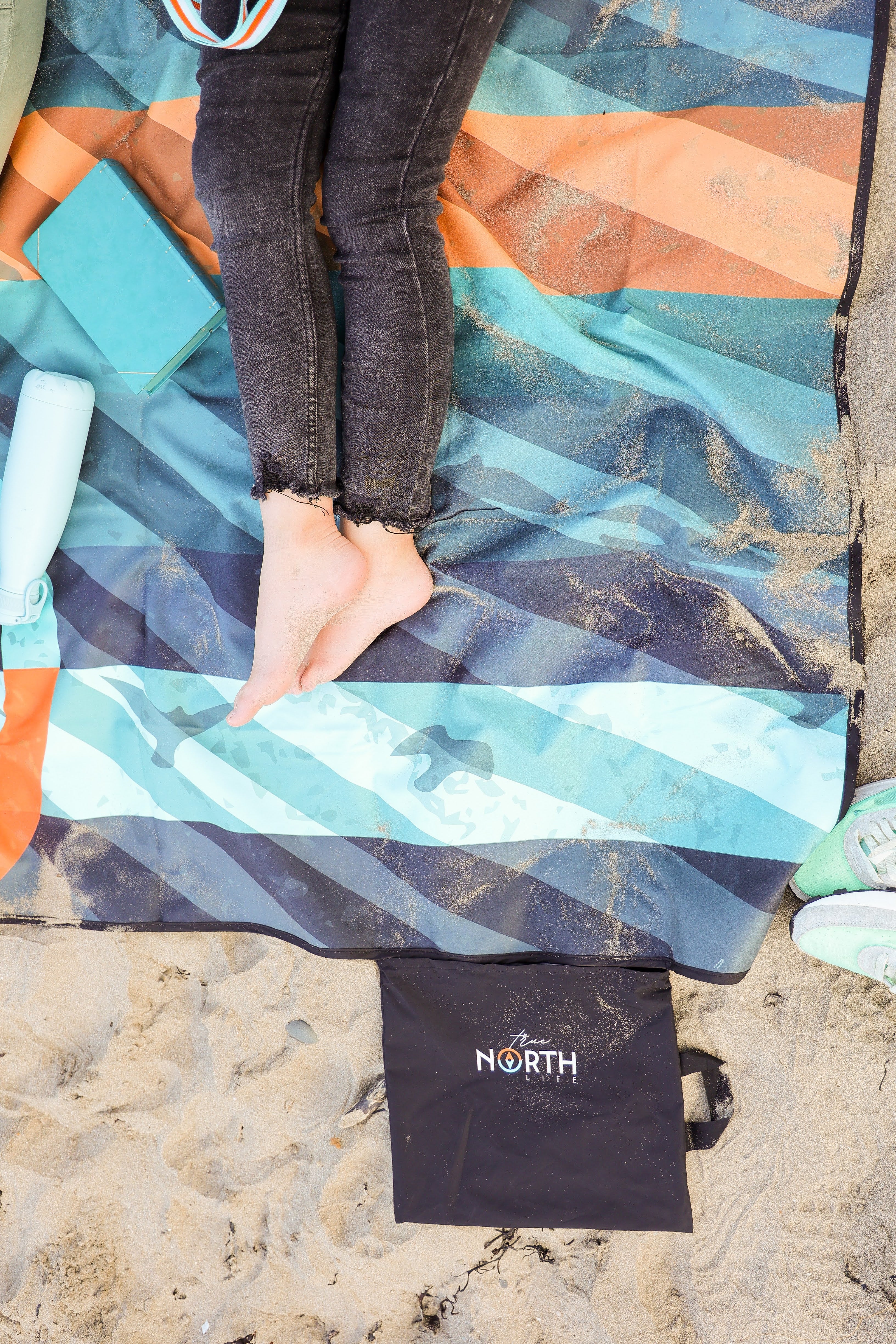 Sustainable waterproof picnic blanket made from recycled polyester, oversized yet packable as it folds flat into a laptop size to slide into a backpack. Zip corner pocket and stake loops and sand pockets to keep it in place. 