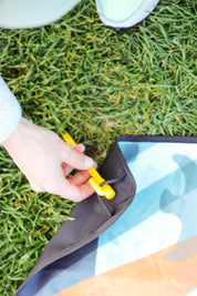 Sustainable waterproof picnic blanket made from recycled polyester, oversized yet packable as it folds flat into a laptop size to slide into a backpack. Zip corner pocket and stake loops and sand pockets to keep it in place. 