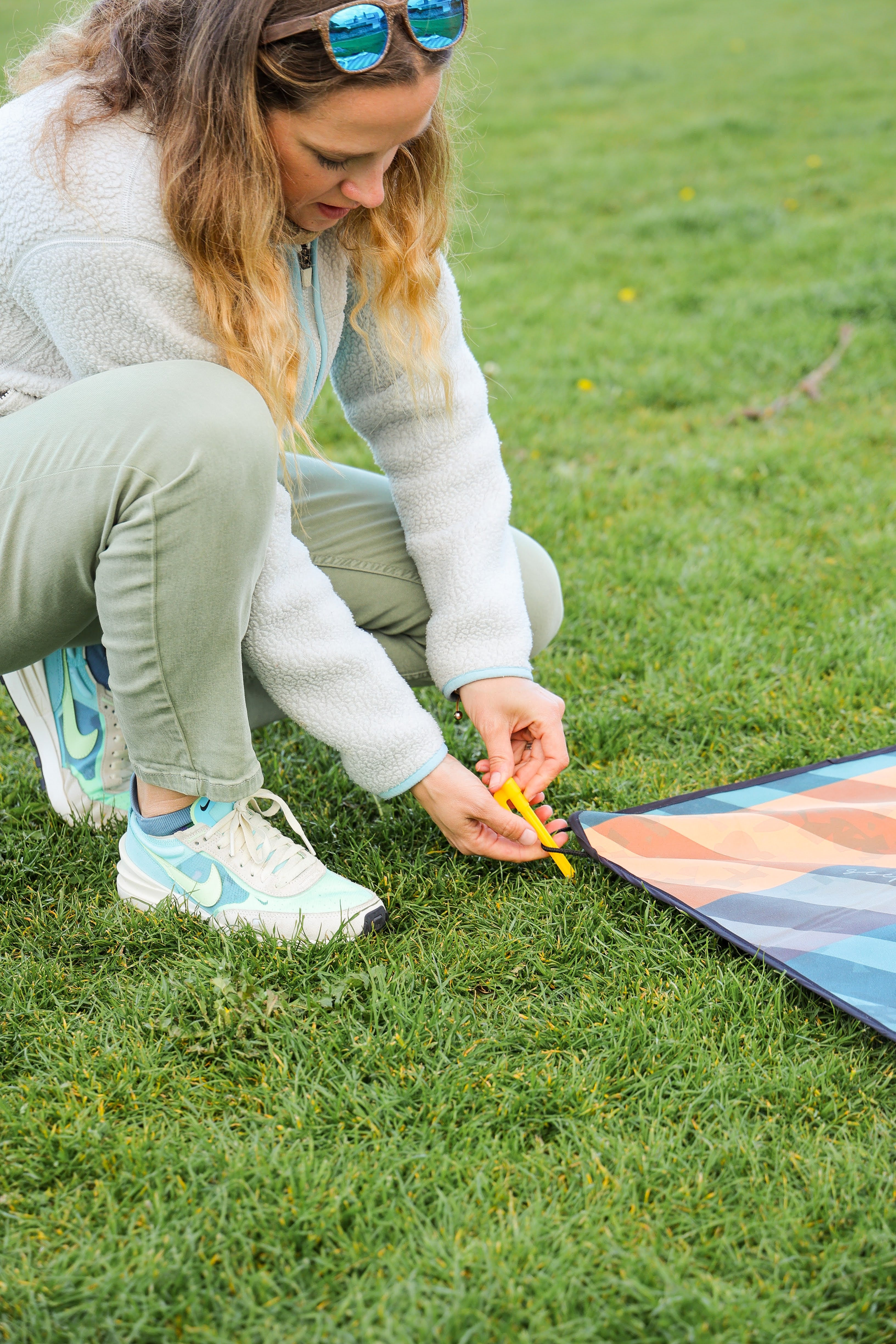 Sustainable waterproof picnic blanket made from recycled polyester, oversized yet packable as it folds flat into a laptop size to slide into a backpack. Zip corner pocket and stake loops and sand pockets to keep it in place. 