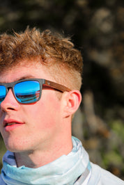 This sustainable rectangular frame is made with a speckled charcoal wheatstraw frame and walnut wood temple and is fitted with UV400 polarised lenses in two colours, smoke and mirrored sky blue. It's lightweight, comfortable and eco-friendly using plastic alternative materials. 