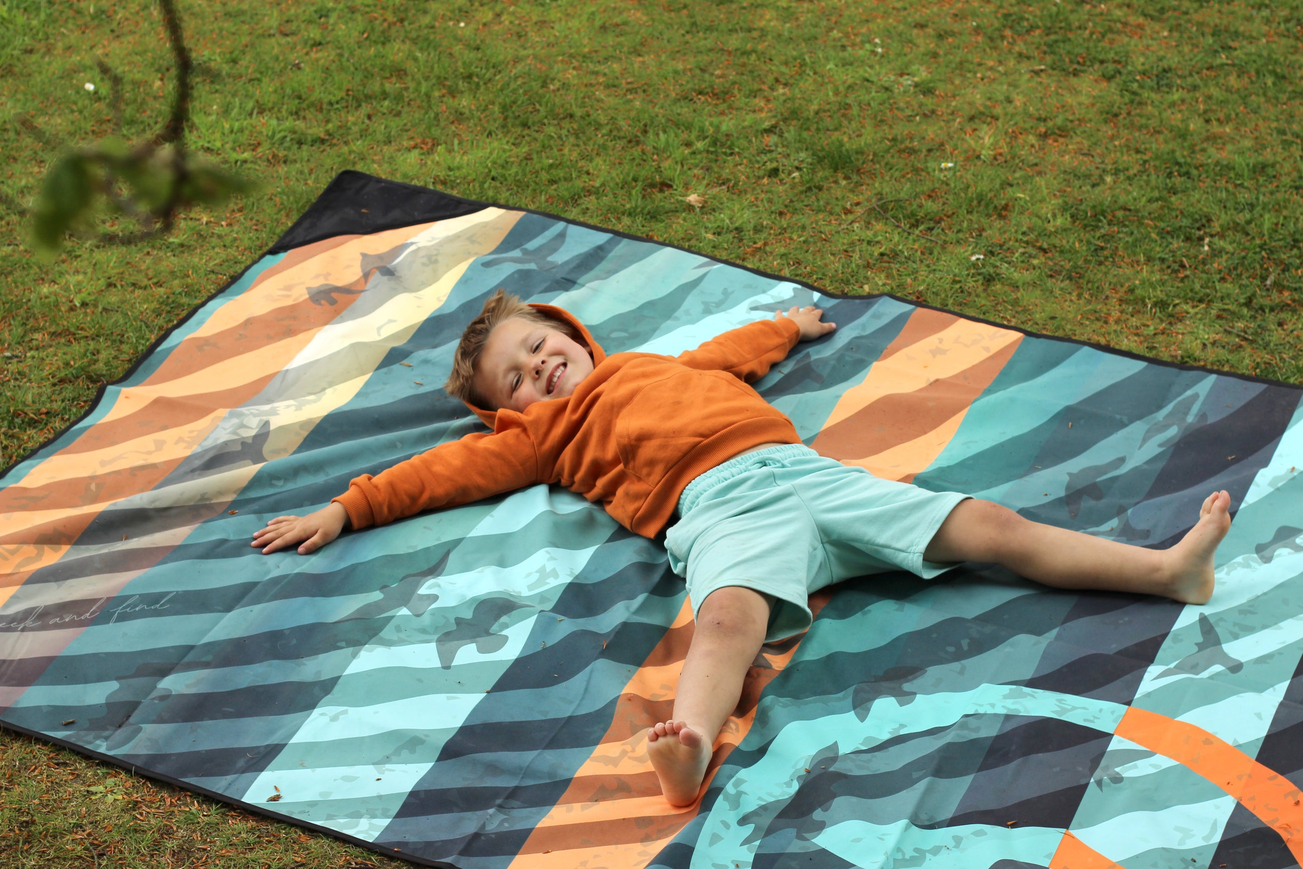 Sustainable waterproof picnic blanket made from recycled polyester, oversized yet packable as it folds flat into a laptop size to slide into a backpack. Zip corner pocket and stake loops and sand pockets to keep it in place. 