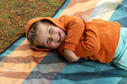 Sustainable waterproof picnic blanket made from recycled polyester, oversized yet packable as it folds flat into a laptop size to slide into a backpack. Zip corner pocket and stake loops and sand pockets to keep it in place. 