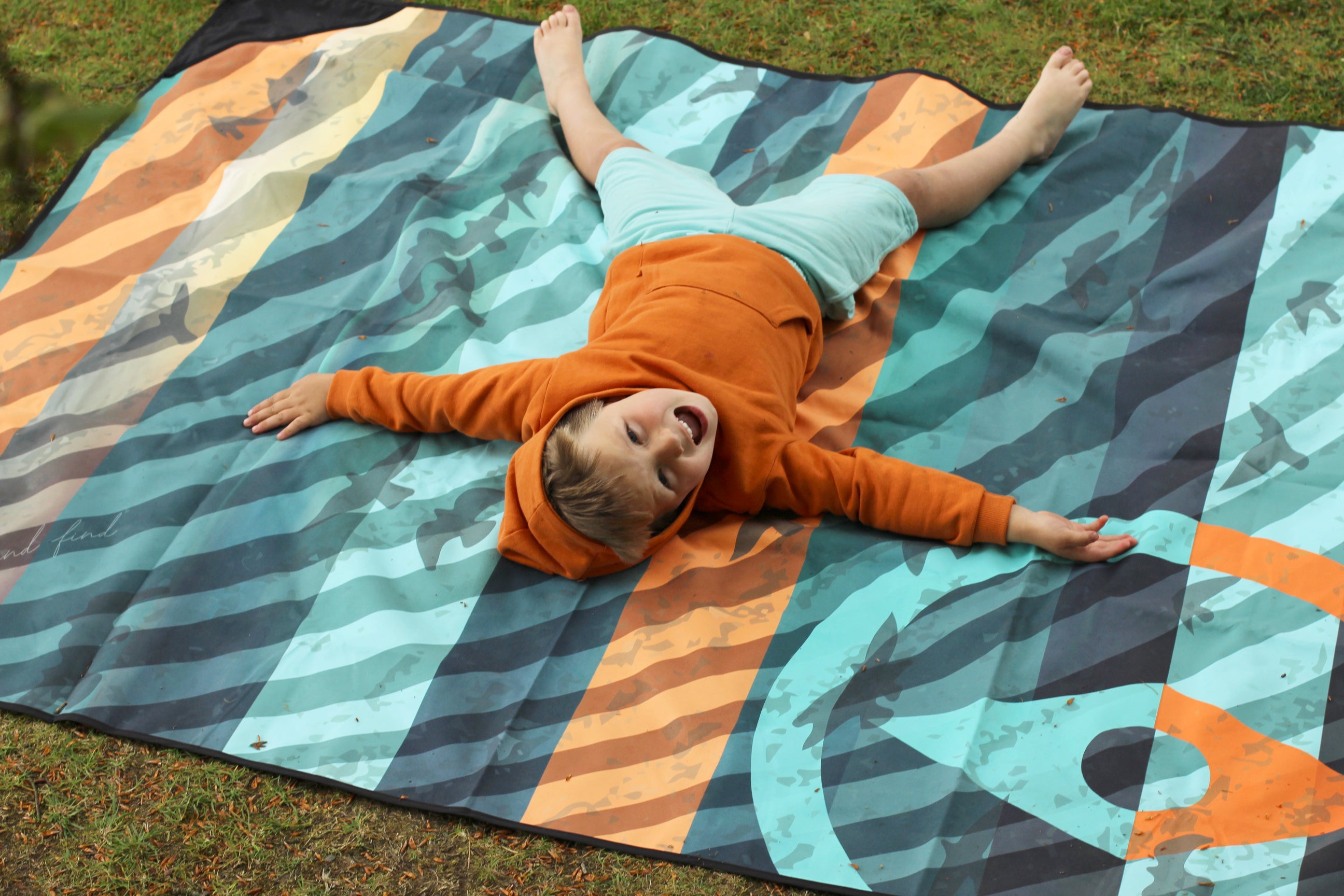 Sustainable waterproof picnic blanket made from recycled polyester, oversized yet packable as it folds flat into a laptop size to slide into a backpack. Zip corner pocket and stake loops and sand pockets to keep it in place. 